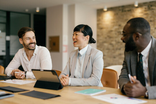 Confident business professionals in meeting with tablet and documents