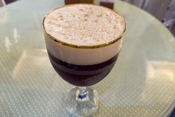 Beer foam on top of dark beer in the glass