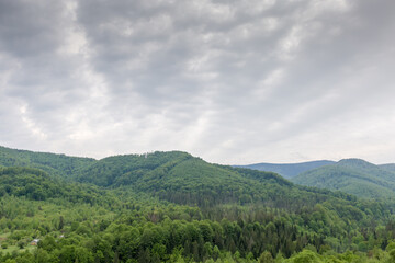 Mountain ranges overgrown with forests against cloudy sky in springtime