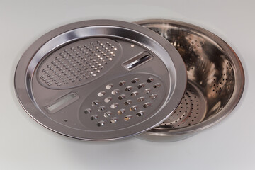 Cookware set of bowl, colander and grater on gray background