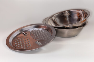 Cookware set of bowl, colander and grater on gray background