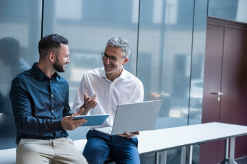 Business manager and colleague discussing project in modern office