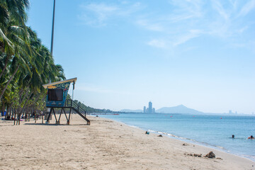 Coastal landscape bang-saen beach with a lifeguard tower, palm trees, blue sky and blue sea. Chon Buri, Thailand
