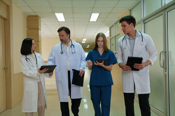 A group of doctors, nurses and staff pose for a photo in a hospital corridor.