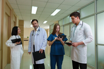 A group of doctors, nurses and staff pose for a photo in a hospital corridor.