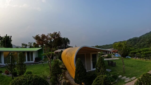 A beautiful sunset timelapse showing the changing sky and golden hour light over unique, modern cabins at a peaceful glamping resort nestled in the mountains of Gapyeong, South Korea.