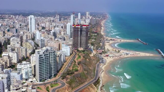 Scenic Aerial view of Netanya cliffside coastline, Israel and its coastline, waves of green ocean hitting the beach, sky rapper building and amazing nature, Main hub of shipping and business coastli