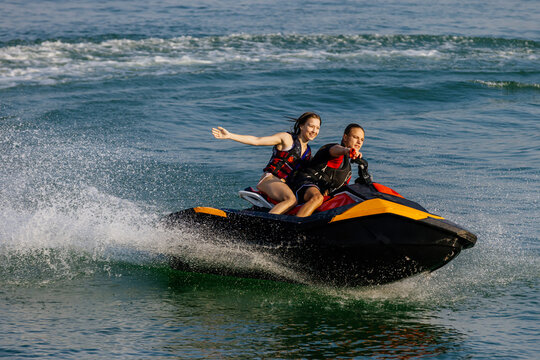 Happy couple riding a jet ski on water. Concept of joy, entertainment and summer adventure.