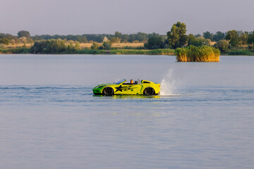 A young man glides across the water on a jet ski designed like a car, enjoying summer waves....