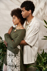Stylish young couple sharing a moment of love surrounded by lush greenery and cozy vibes