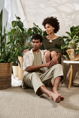 Young couple enjoying intimate moments surrounded by greenery in a stylish indoor setting