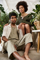 Young couple sharing a cozy moment surrounded by greenery in a stylish indoor space