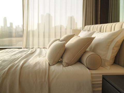 Beige King Size Bed with City View Through Sheer Curtains