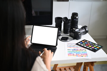 Over shoulder view of graphic designer working on digital tablet with blank screen at desk