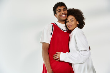 Young couple sharing warmth and joy in a stylish embrace against a minimalist backdrop