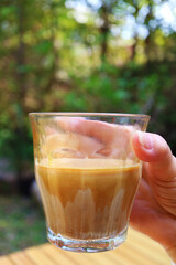Closeup of a Glass of Dirty Latte Coffee in Hand