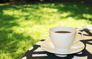 Cup of freshly brewed aromatic hot coffee on garden table