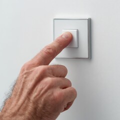 A hand pressing a white light switch on a white wall