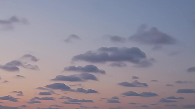 A pastel sunset sky with soft, puffy clouds scattered across a gradient backdrop