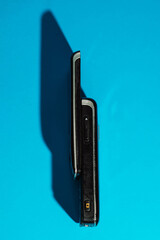 Retro slider phone standing upright on cyan paper with sharp shadow. Minimalist Y2K layout. High...