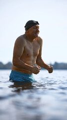 Mature swimmer grimacing from cold water with tense expression. Concept of adult reaction, sensory...