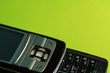 Cropped view of keypad and navigation buttons of an outdated phone on green paper. High quality...