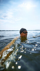 Focused senior swimmer floating calmly with serious face. Concept of endurance training, cold...