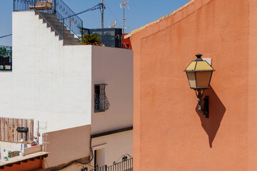 Colorful buildings and a vintage street lamp in Alicante, Spain create a picturesque urban scene....
