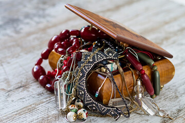 An antique wooden jewelry box filled with necklaces and costume jewelry