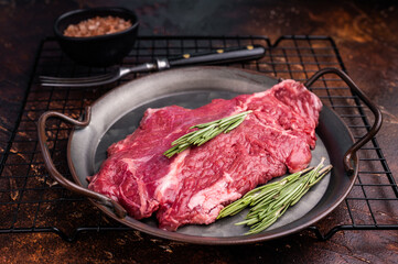 Raw hanger tender beef steak, skirt steak with rosemary on steel tray. brown background. top view