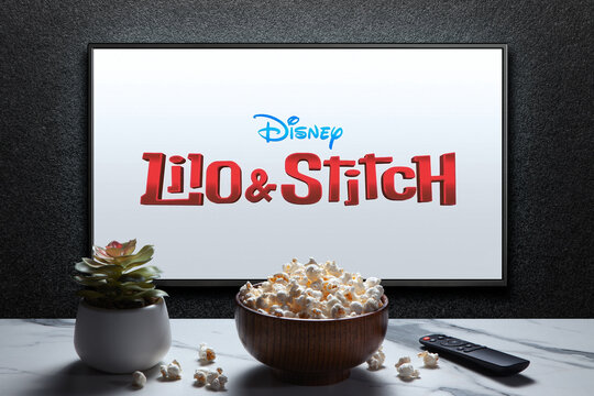 Lilo and Stitch trailer or movie on TV screen. TV with remote control, popcorn bowl and home plant. Astana, Kazakhstan - May 23, 2025.