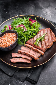 Grilled Top blade steak with salad, beef shoulder meat on a plate. black background. top view