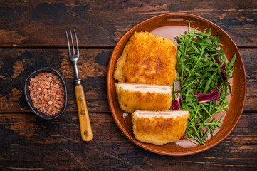 Chicken Fried cordon bleu cutlet on plate with salad. wooden background. top view