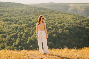 A stylish model stands elegantly in a stunning scenic landscape, showcasing a beautiful, serene...