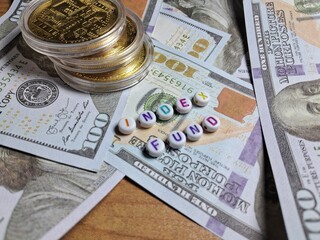 Colorful letter beads spelling “Index Fund” placed on US dollar bills  and golden crypto coins