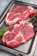 Raw pork neck meat steaks on steel tray. grey background. top view