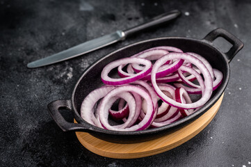 Fresh Raw onion rings in skillet. black background. top view