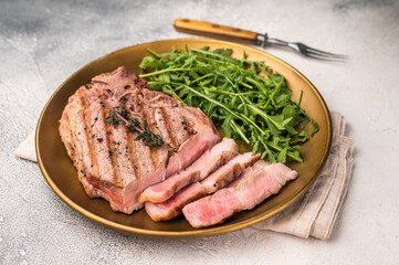 Roasted BBQ pork neck meat steak on plate with salad. grey background. top view