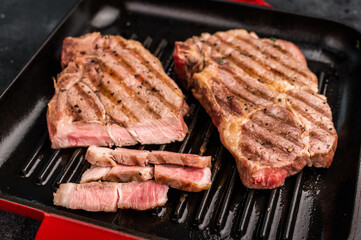 Fried on grill skillet pork tender steak, neck meat. black background. top view