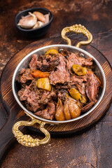 Slow cooked Beef Cheek, Braised meat with vegetables in a skillet. brown background. top view