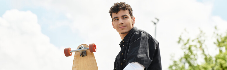 Young man enjoying a sunny day at the park while holding his skateboard in hand