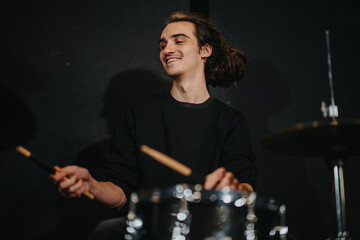 A drummer enthusiastically plays the drums during a lively band rehearsal in a studio setting.