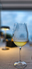 A glass of chilled white wine against a blurred background in a restaurant on the Ligurian Riviera in the summer of 2025.