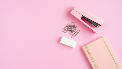 Elevated Still Life Composition of Pink Stapler, Paper Clips, Eraser, and Notebook on a Light Pink Background for Office Supplies and Stationery Concepts with Copy Space