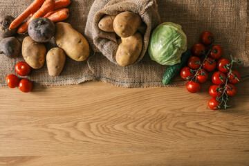 Top view of assorted fresh vegetables on a wooden table: carrots, beets, potatoes, cabbage,...