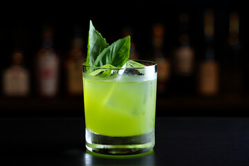 Refreshing green cocktail with fresh basil garnish on a bar counter
