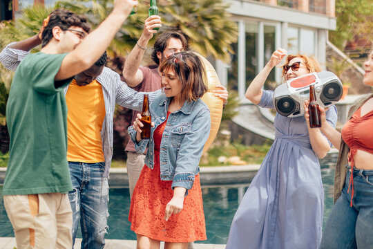 Friends enjoying drinks and music by the pool during a summer pool party