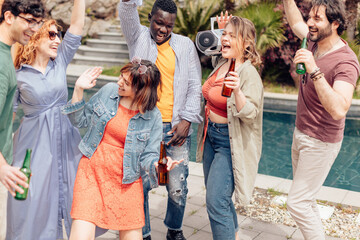 Friends dancing at pool party with beer and boombox, enjoying summertime together