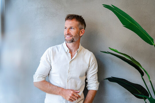 Confident business professional smiling indoors with plant in modern office