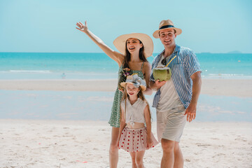 Family on a tropical beach vacation hold playing with an inflatable rubber ring. A beautiful family walks together on a tropical paradise beach.	